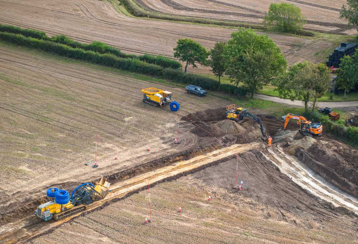 Aerial view of land drainage work in progress, showing GPS-guided trenching machinery and excavators facilitating