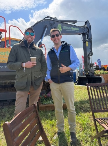 Two men standing in front of a William Morfoot Ltd excavator at the Cereals 2026