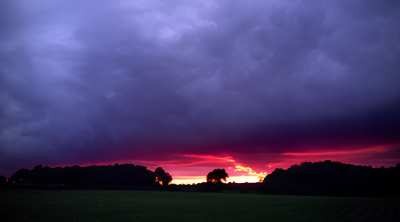 Dark, dramatic storm clouds gathering over agricultural farmland, illustrating the volatile climate conditions