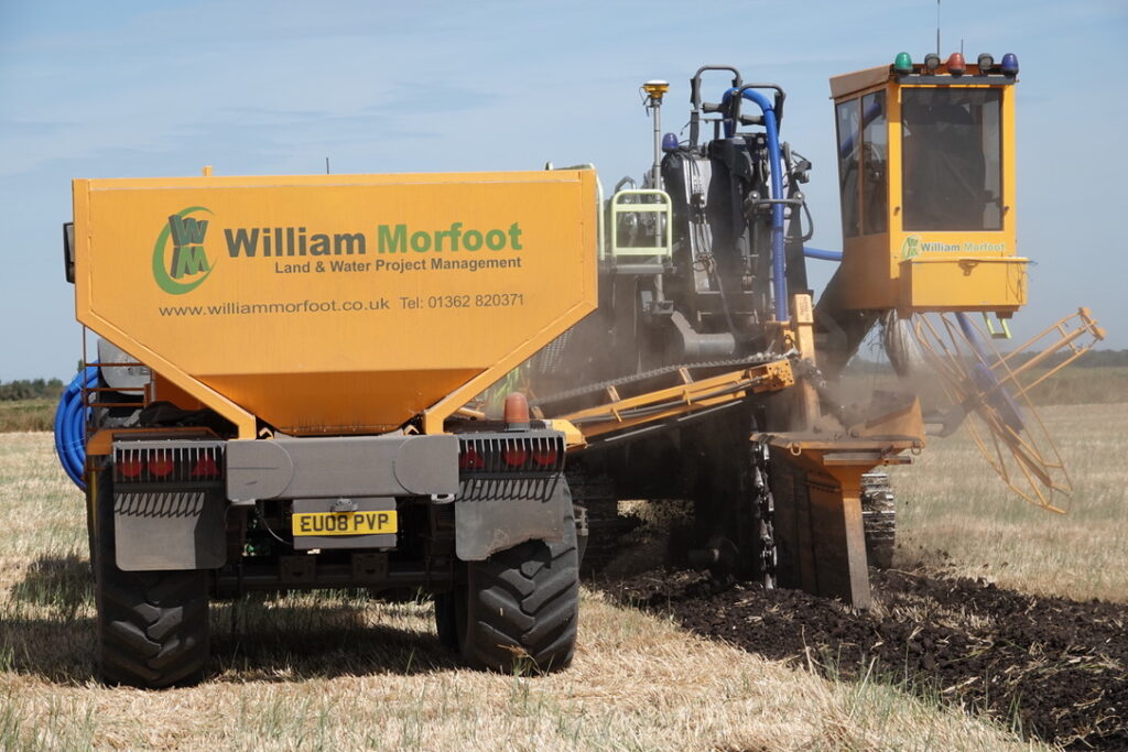 Perforated lateral drains being installed across a field as part of an agricultural land drainage system in the UK